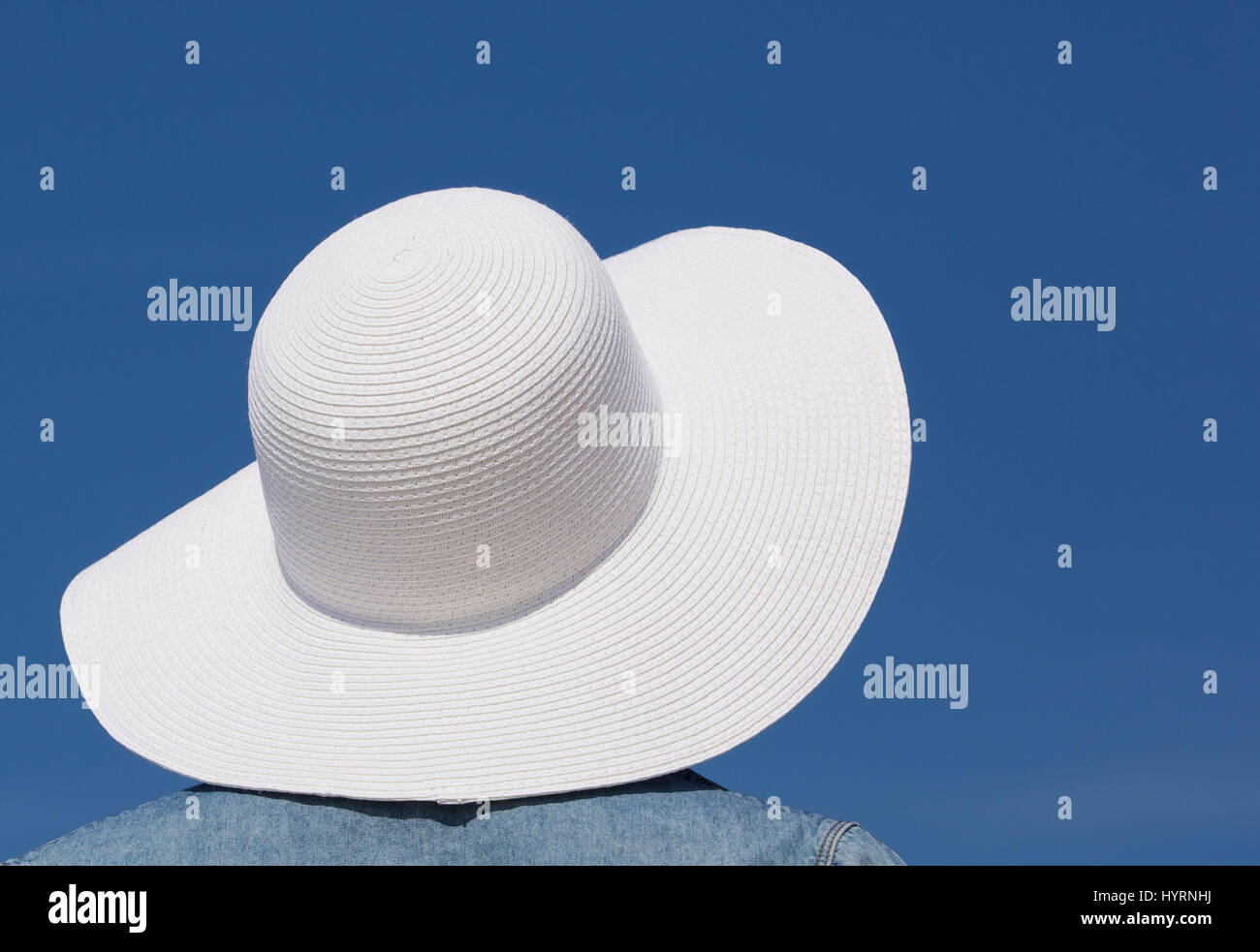 Close up portrait of female with white sun hat and blue sky background Stock Photo