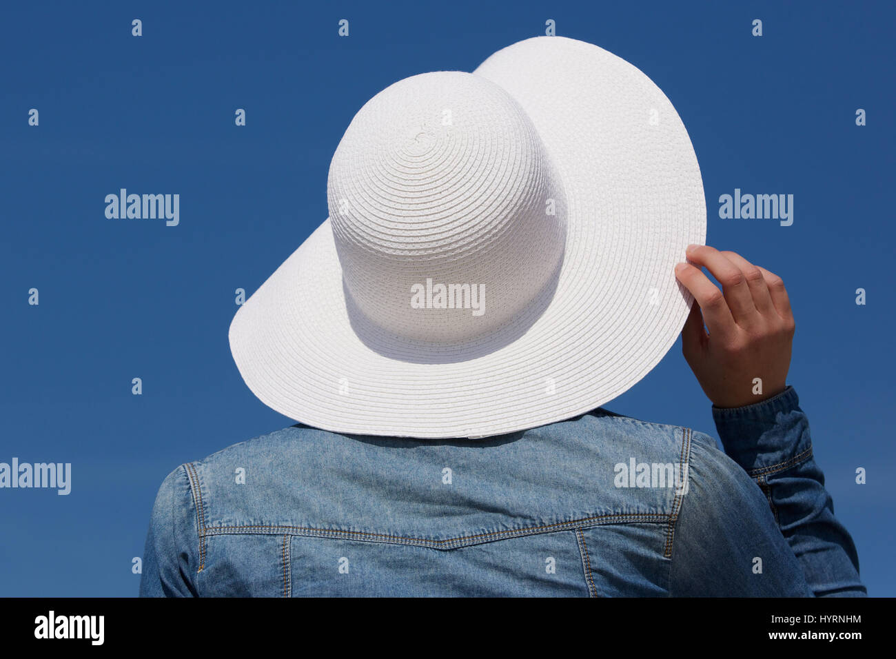 Close up portrait of the back of a young woman with white sun hat from behind Stock Photo