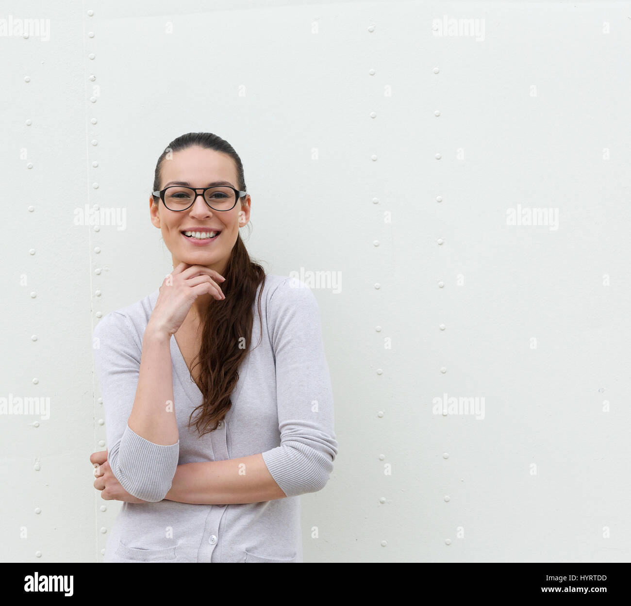 Portrait of a young woman with glasses smiling against white background ...
