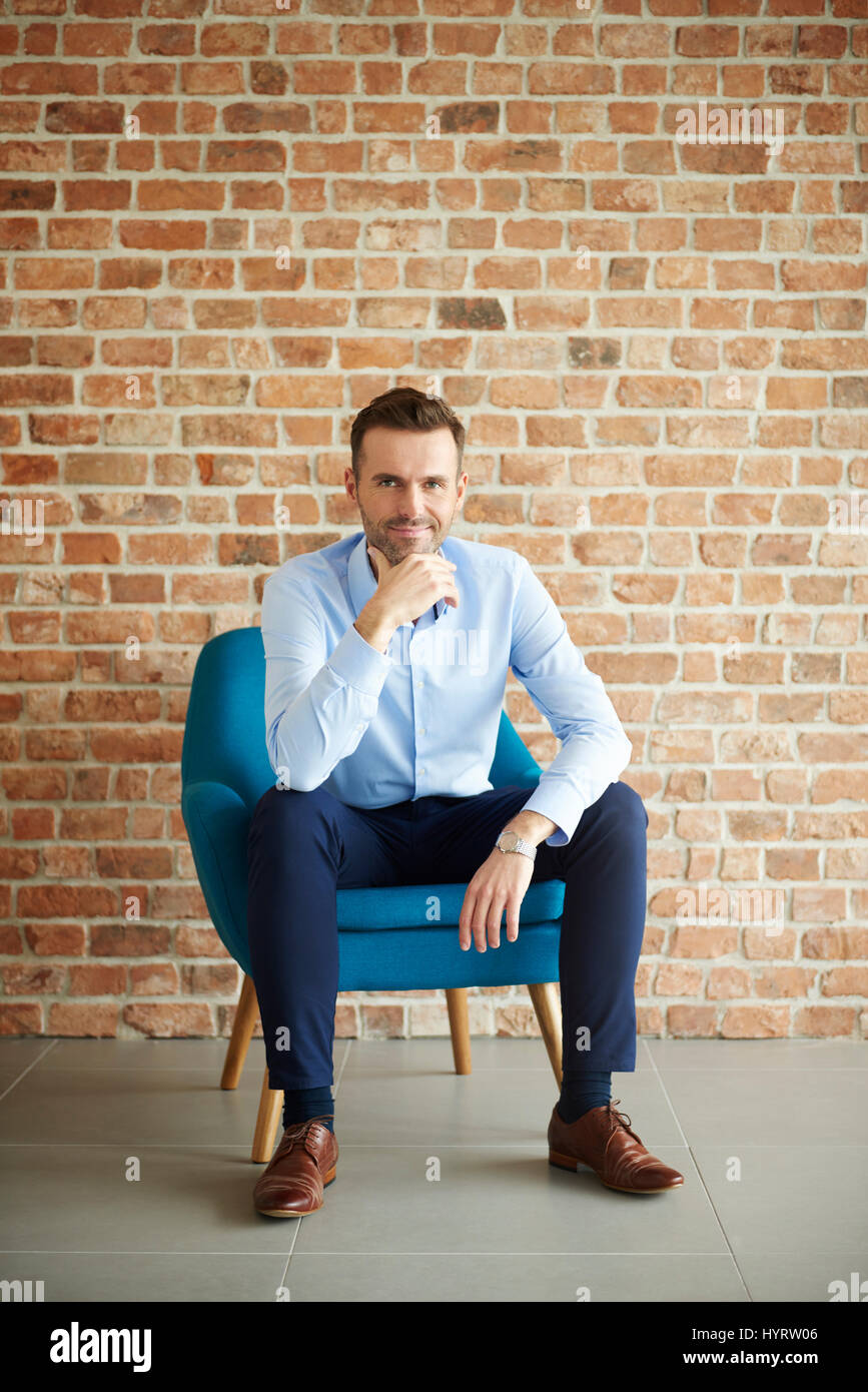 Man in formal clothes sitting in armchair Stock Photo