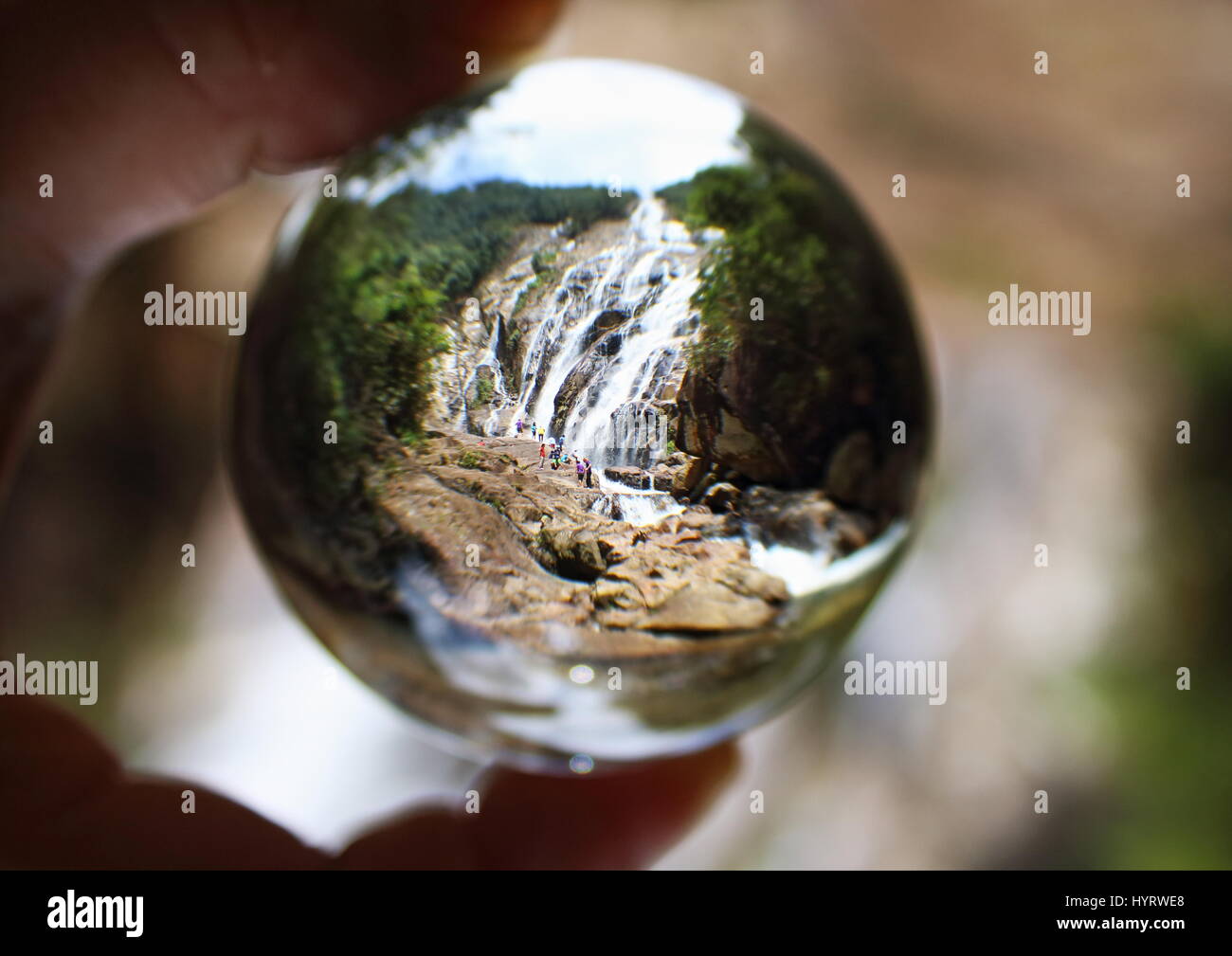 Glass ball photography with an image of the cascading Chemerong Waterfall in Terengganu, Malaysia taken inside the glass ball. Stock Photo