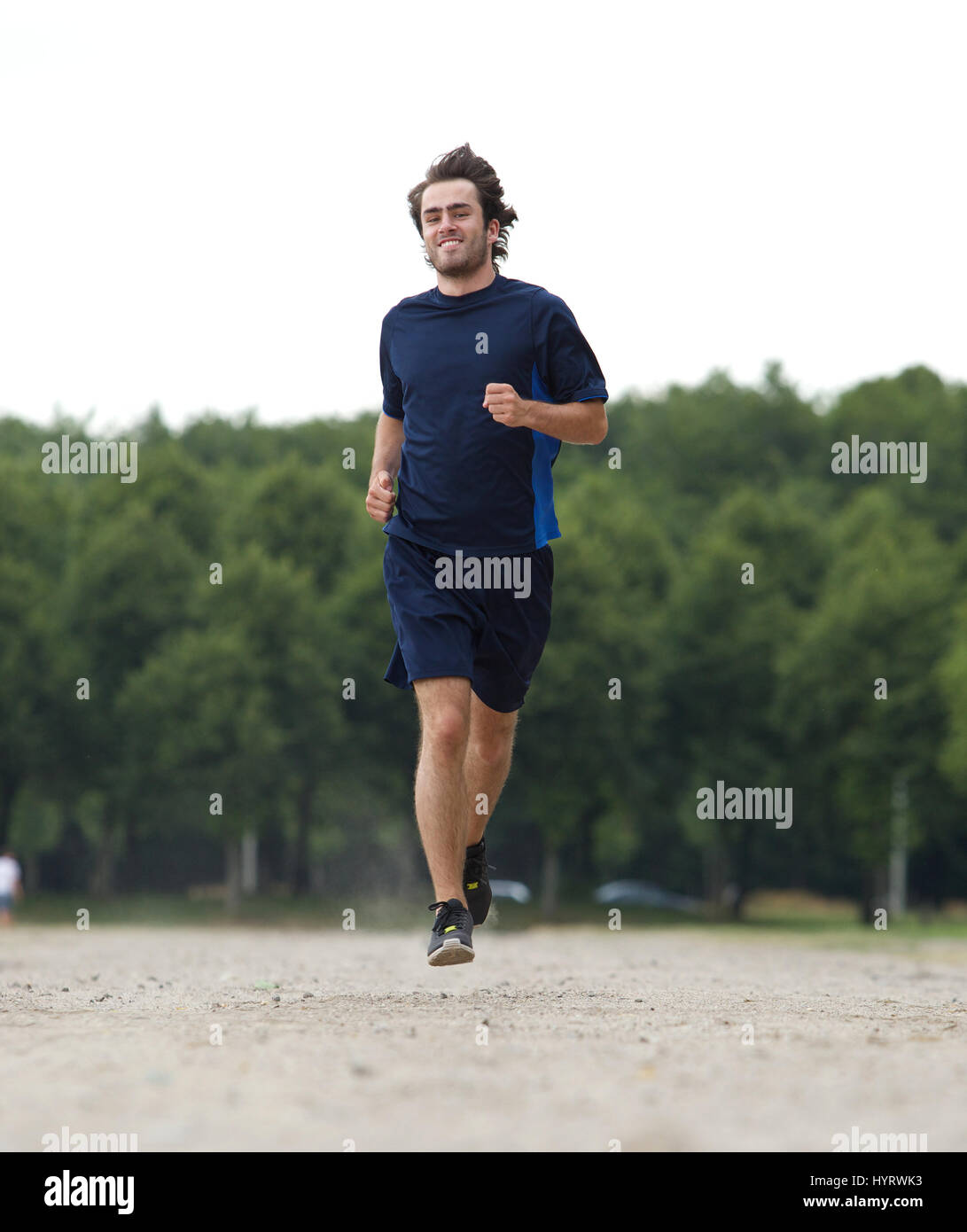 Active young man smiling and jogging outdoors Stock Photo