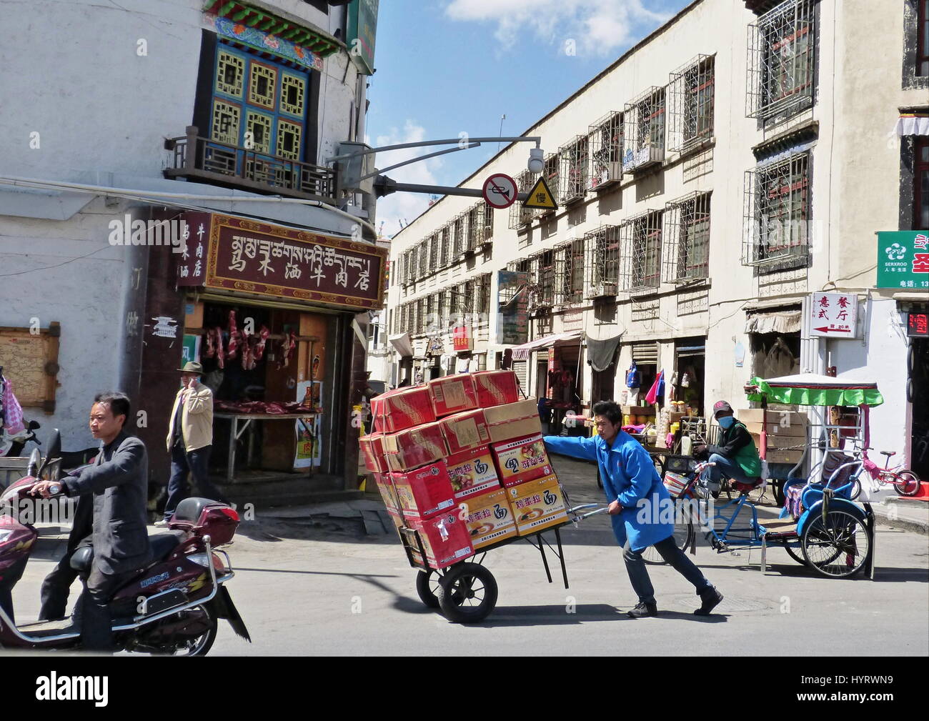 A street scene in Lhasa, Tibet with a vendor pushing his wares and other modes of transport Stock Photo