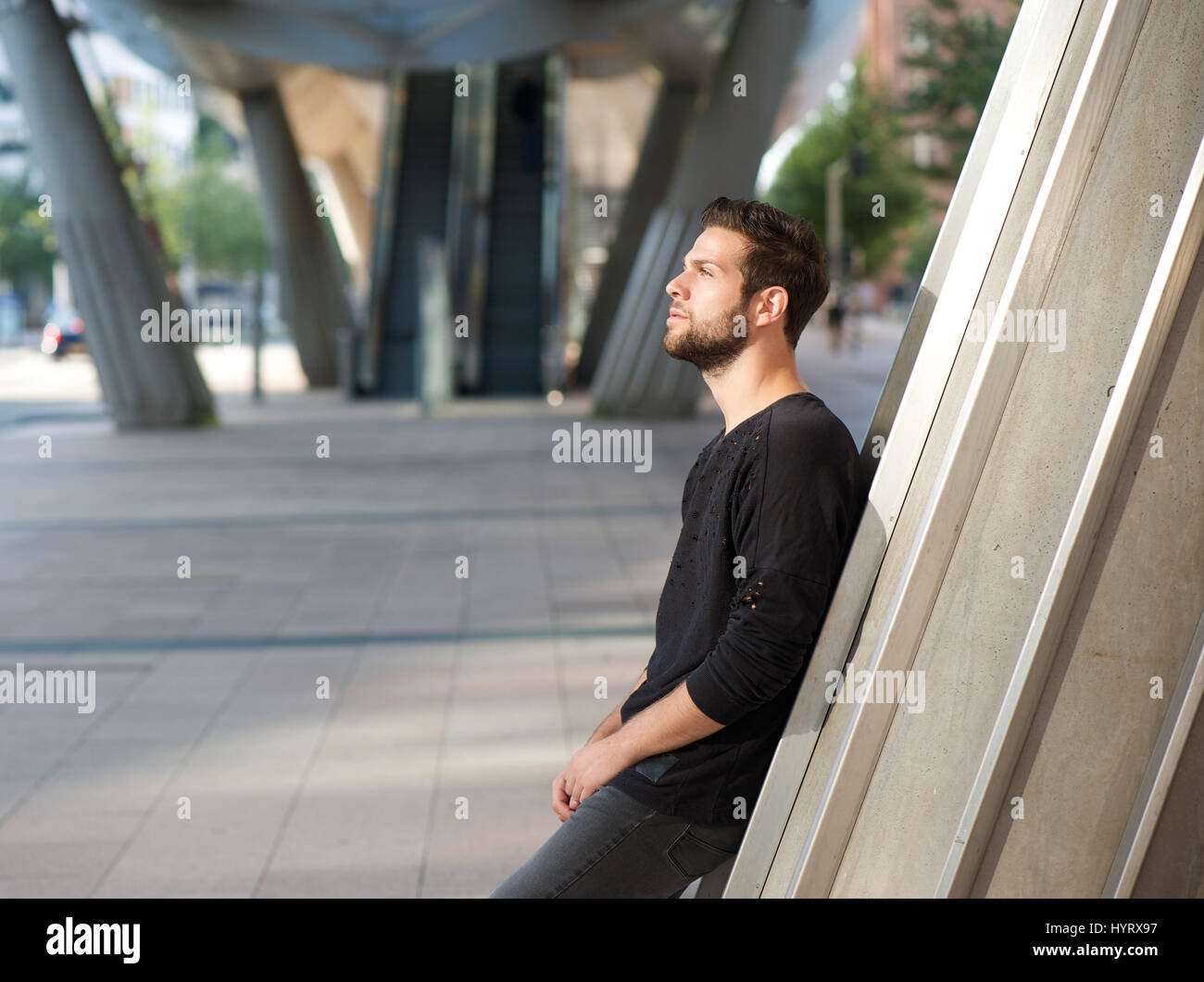 Side view portrait of a handsome young man standing outdoors in the city Stock Photo