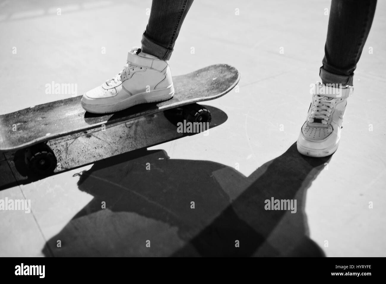Legs of teenage urban girl on skateboard at skate park on the evening