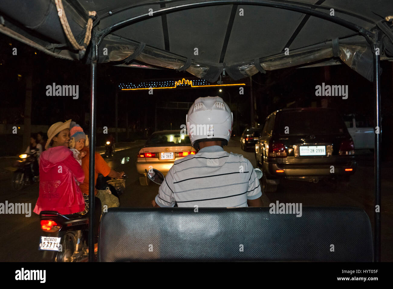 Horizontal streetview of a tuk-tuk driving through traffic at night in Siem Reap Stock Photo