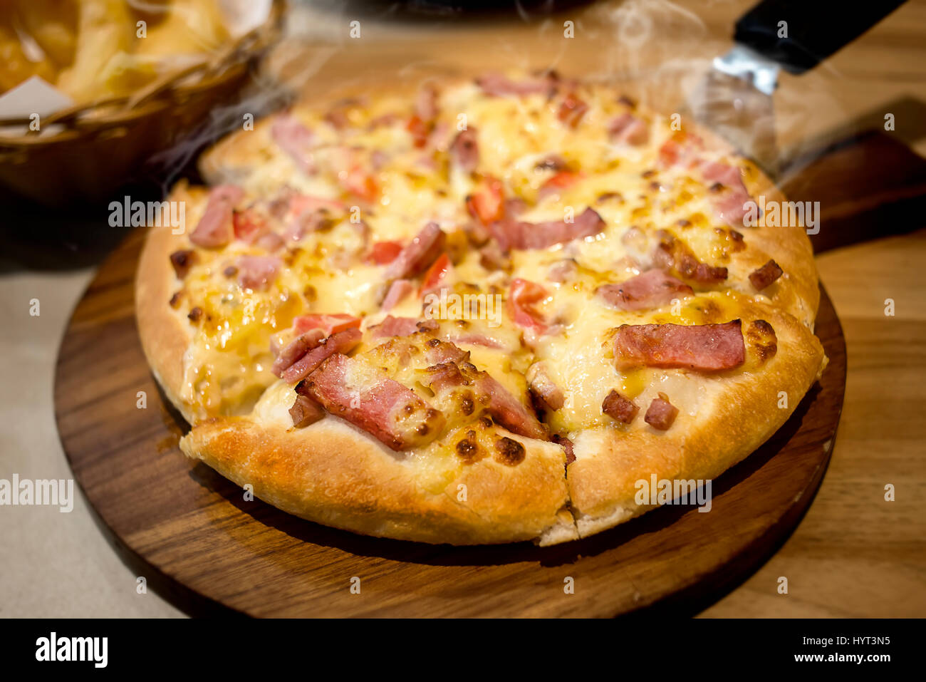 Home made pizza cheese and ham hot and smoke on serve photo in indoor very low lighting . Stock Photo