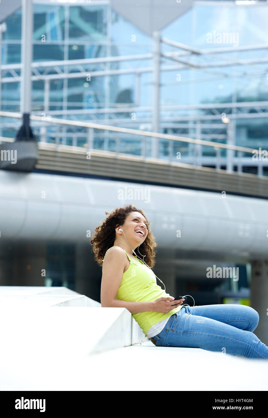 Portrait of a young woman listening to music on earphones outdoors ...