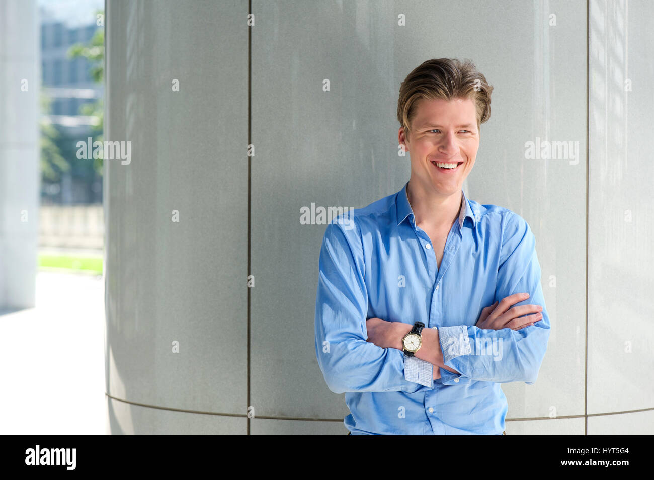 Close up portrait of a young businessman smiling with arms crossed ...