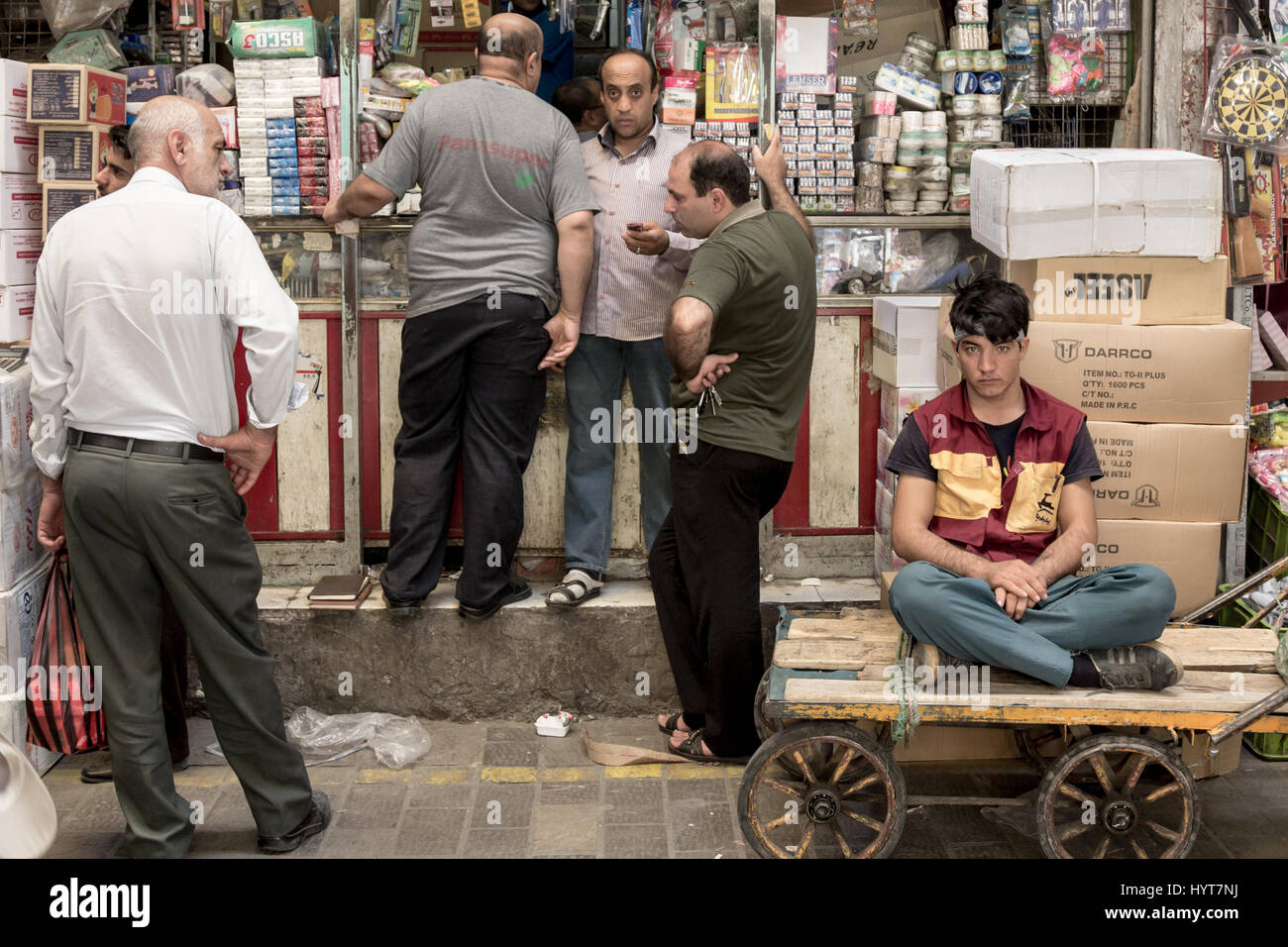 TEHRAN, IRAN - AUGUST 14, 2016: Merchants and delivery boys having a break and discussing in a covered street of Tehran bazaar   Old and young iranian Stock Photo