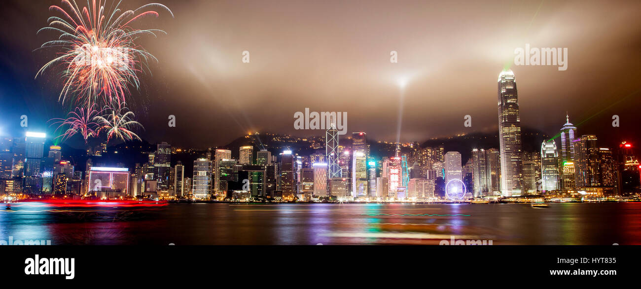 Panorama view of Hong Kong skyline with lasers, floodlights and fireworks illuminating the night skies on Victoria Harbor. Viewed from downtown Tsim S Stock Photo