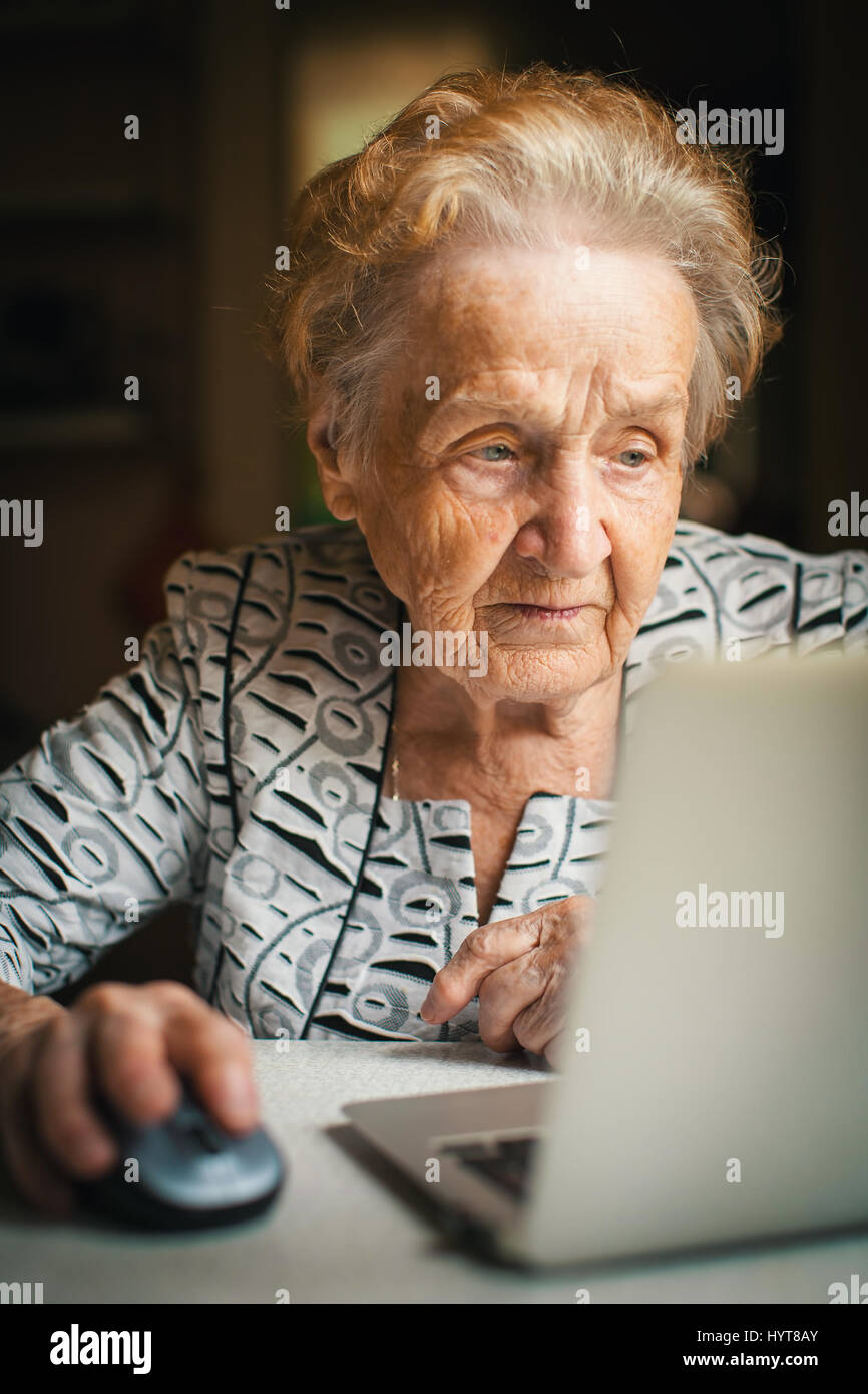 Retired woman working on computer at home. Stock Photo