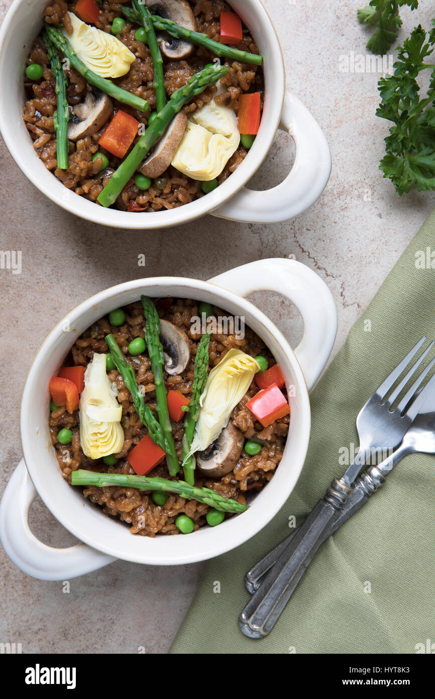 Two bowls of vegan paella with asparagus, mushrooms and artichoke