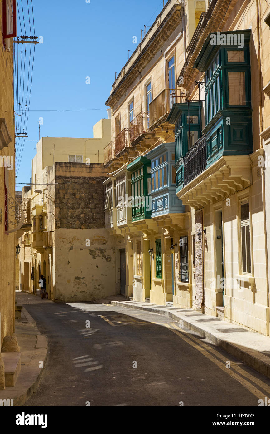 The narrow paved street with the typical Maltese style green balconies on the residential houses. Rabat. Malta Stock Photo