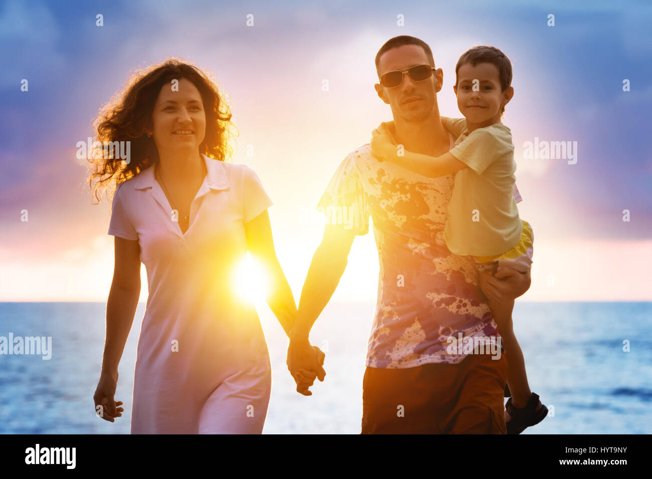 Happy family walking at sunset beach Stock Photo