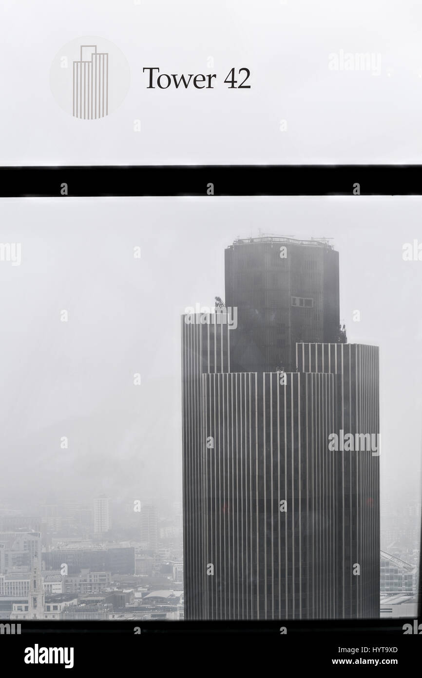 View of Tower 42  through a window of the Walkie-Talkie skyscraper building at 20 Fenchurch Street, city of London, England, on a misty morning. Stock Photo