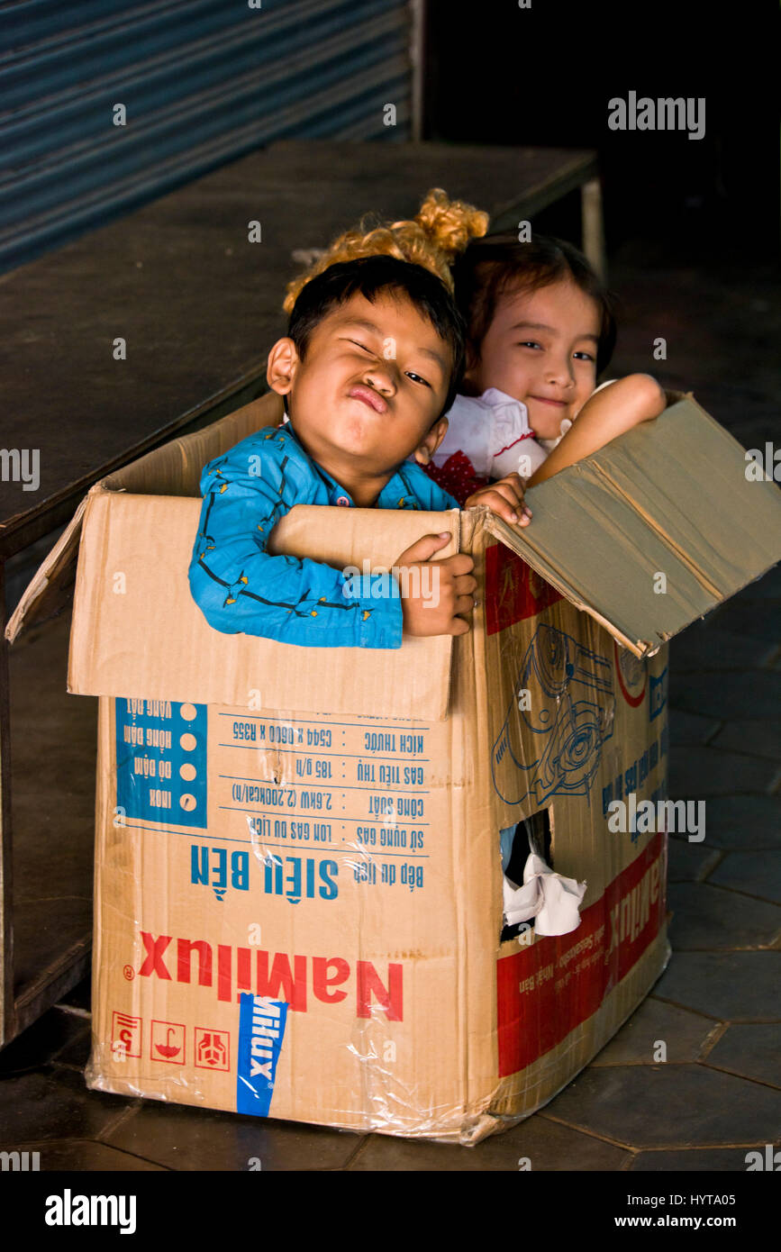 Vertical portrait of children playing inside a cardboard box in Cambodia. Stock Photo