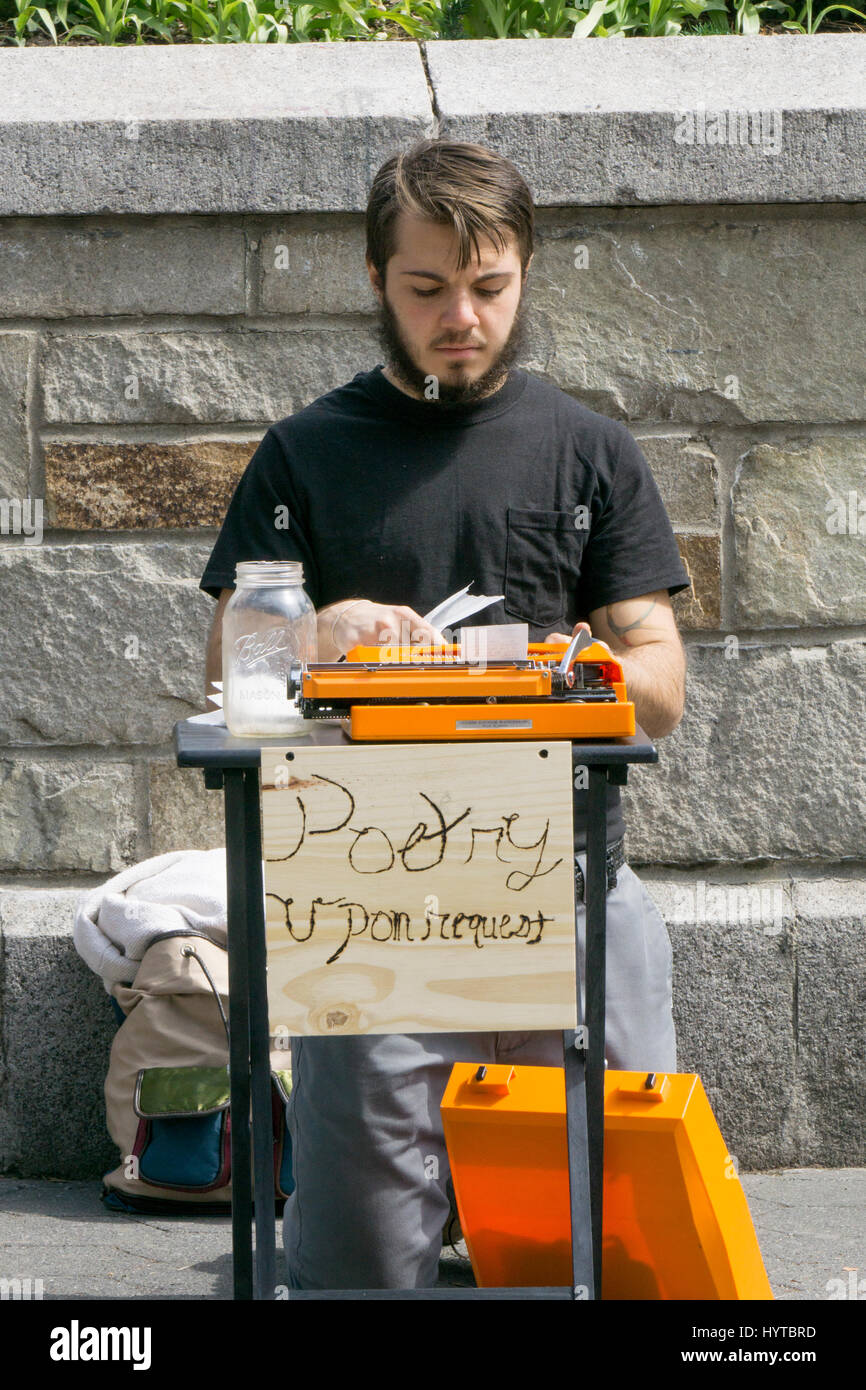 A young man writing poetry upon request for donations in Union Square Park in Manhattan, New York City. Stock Photo