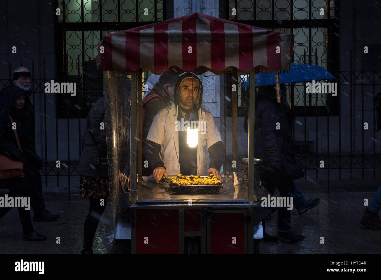 ISTANBUL, TURKEY - DECEMBER 30, 2015: Picture of an young chestnut seller on a winter evening under the snow  Young chestnut seller near Eminonu squar Stock Photo