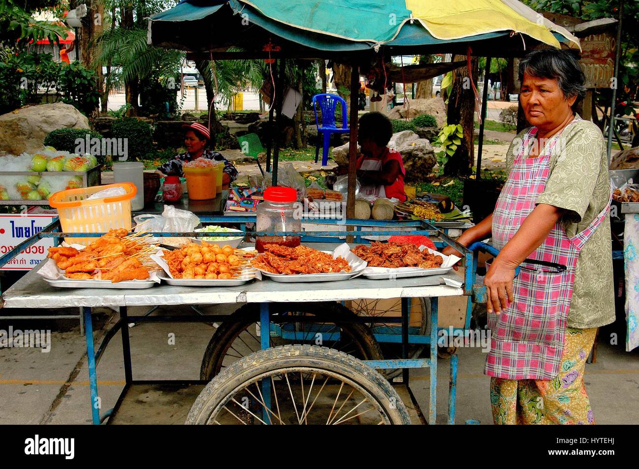 Nakhon Pathom, Thailand - December 27, 2005:  Woman street vendor pushing her cart filled with fried food at Wat Dai Lom Stock Photo