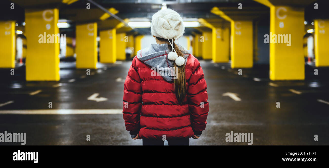 Girl wearing white hat and red jacket standing in the public car garage Stock Photo