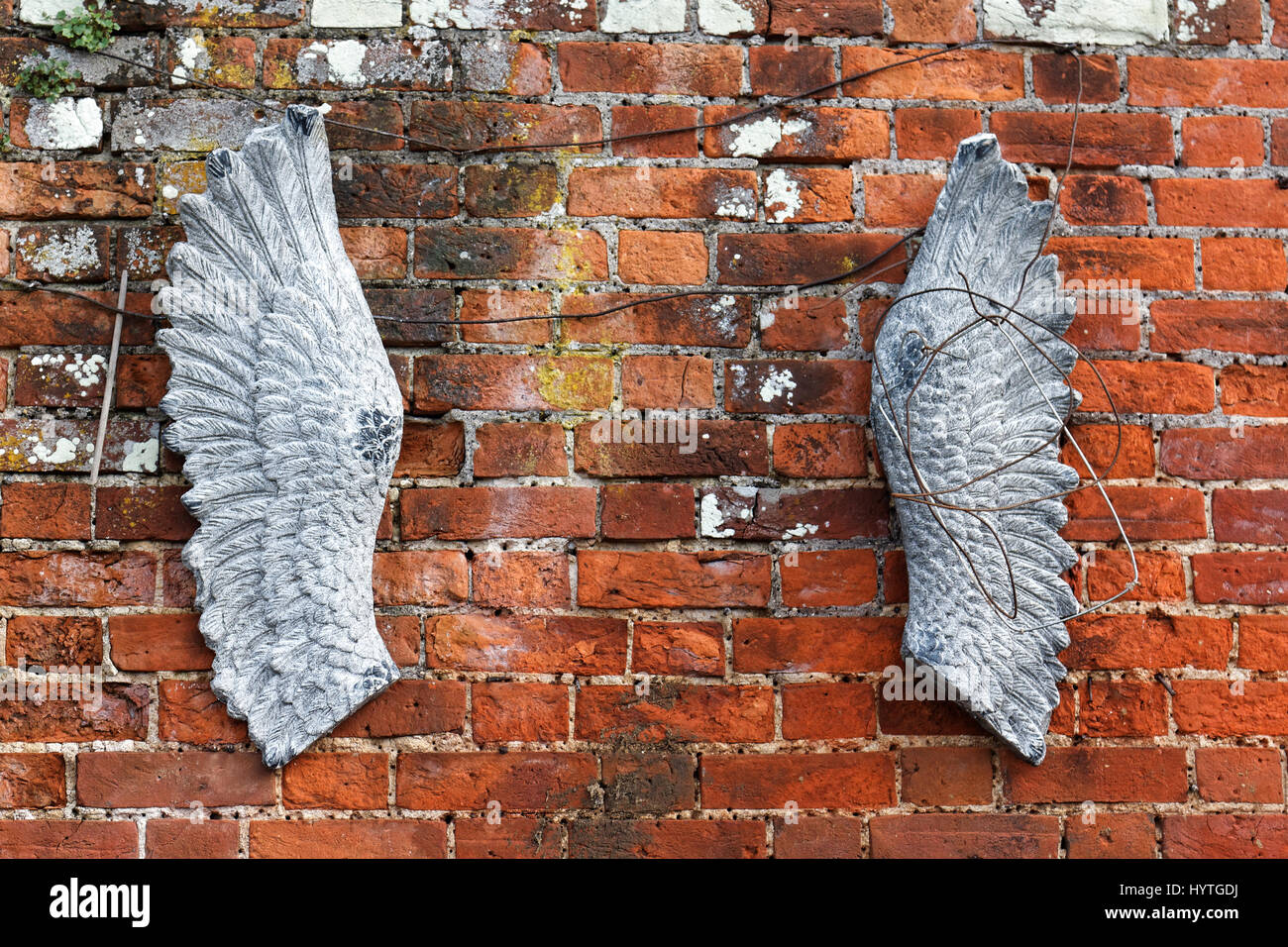 Angel's wings hanging on a red brick wall background Stock Photo - Alamy