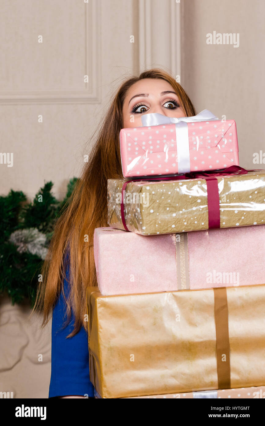 beautiful girl with a big stack of gifts in her arms. studio vertical close-up portrait. Stock Photo