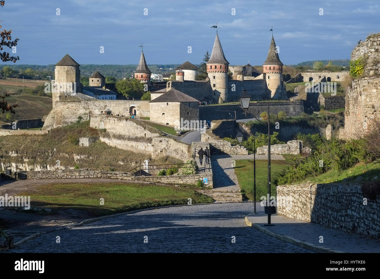 View of the Most Zamkowy and Castle of Kamianets-Podilskyi in Western Ukraine taken on a sunny autumn day. The cobbled street leads the eye across the Stock Photo