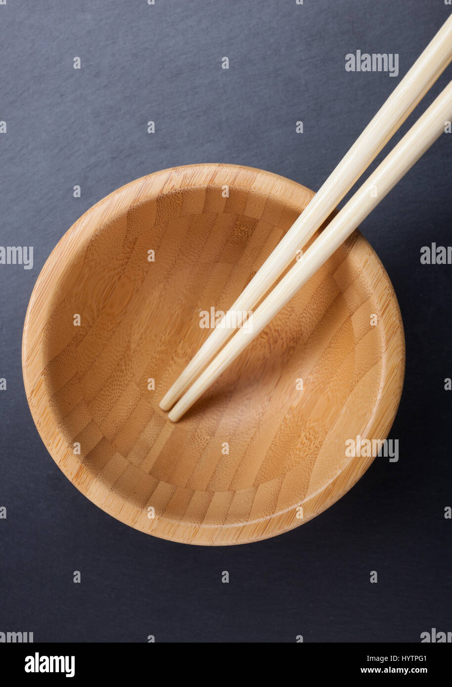 Chinese chopsticks with empty wooden bowl on sblack late. Stock Photo