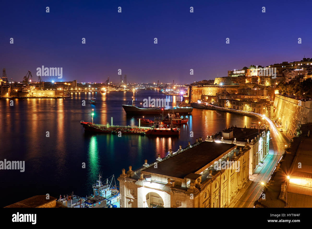 The night view of Grand Harbour with the cargo ships moored near St. Barbara Bastion from the Lower Barrakka Gardens, Valletta. Stock Photo