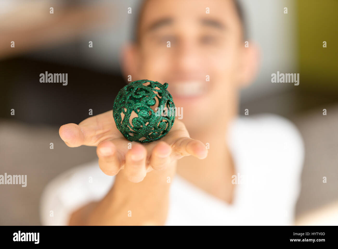 Closeup of green ball on palm of incognito smiling man in white t