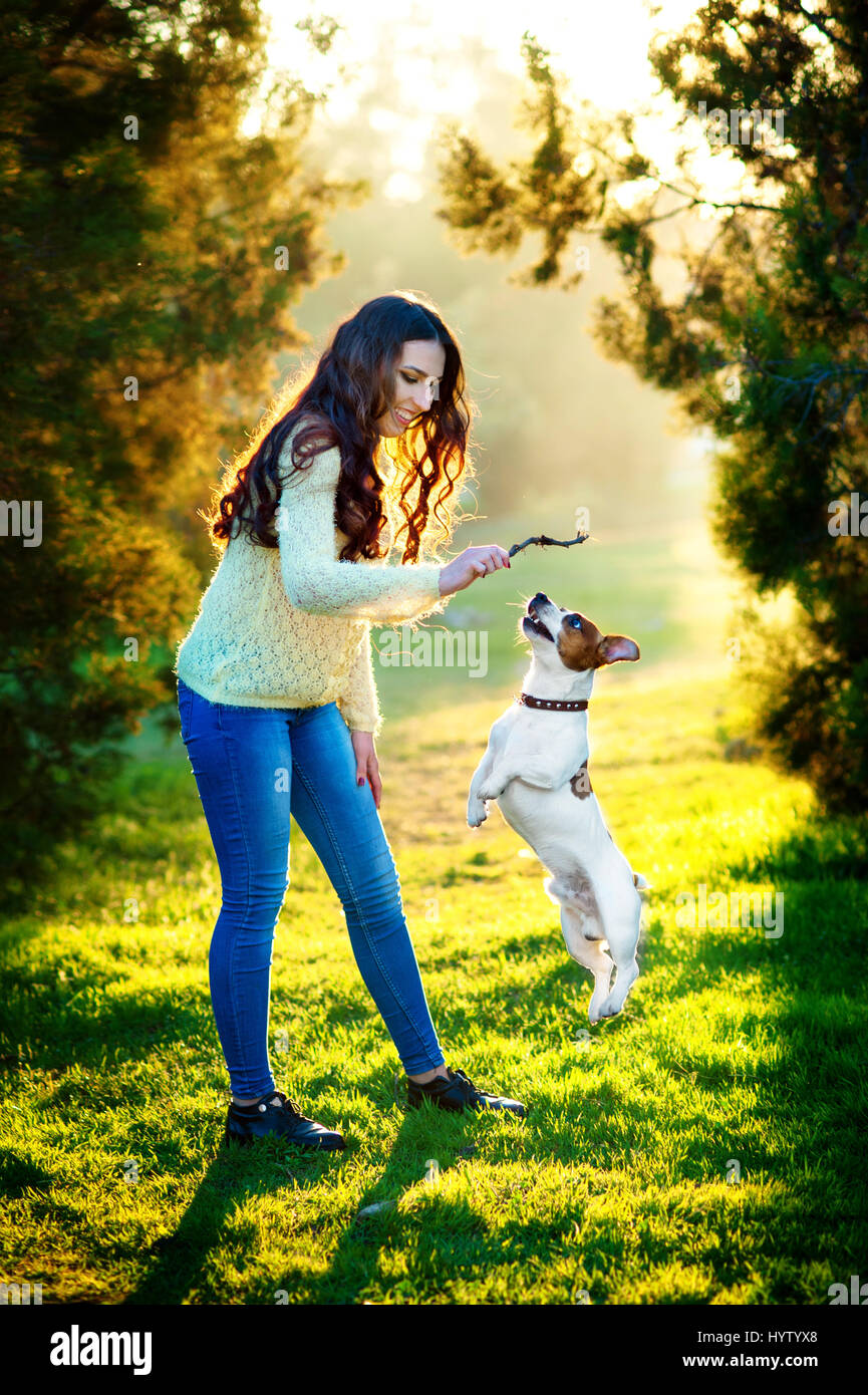 Young woman walking with a dog playing training, jumping dog. Jack