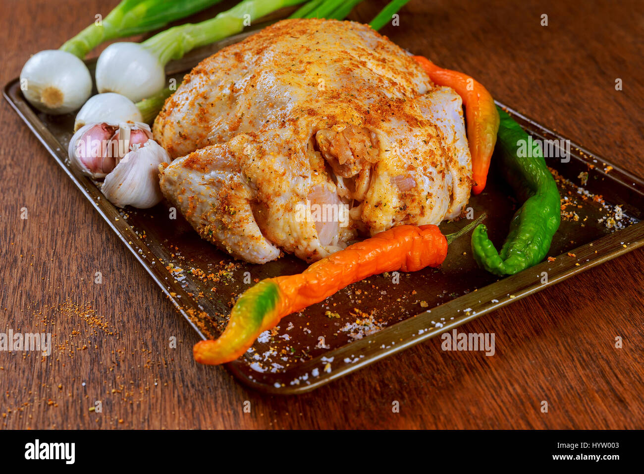 Uncooked whole chicken in baking form with chopped vegetables carrots sweet potatoes onions, seasoned, prepared for cooking Stock Photo