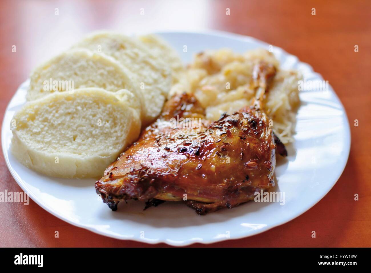 A Plate of Roast Duck Drumstick with Dumplings and Stewed White Cabbage. Stock Photo