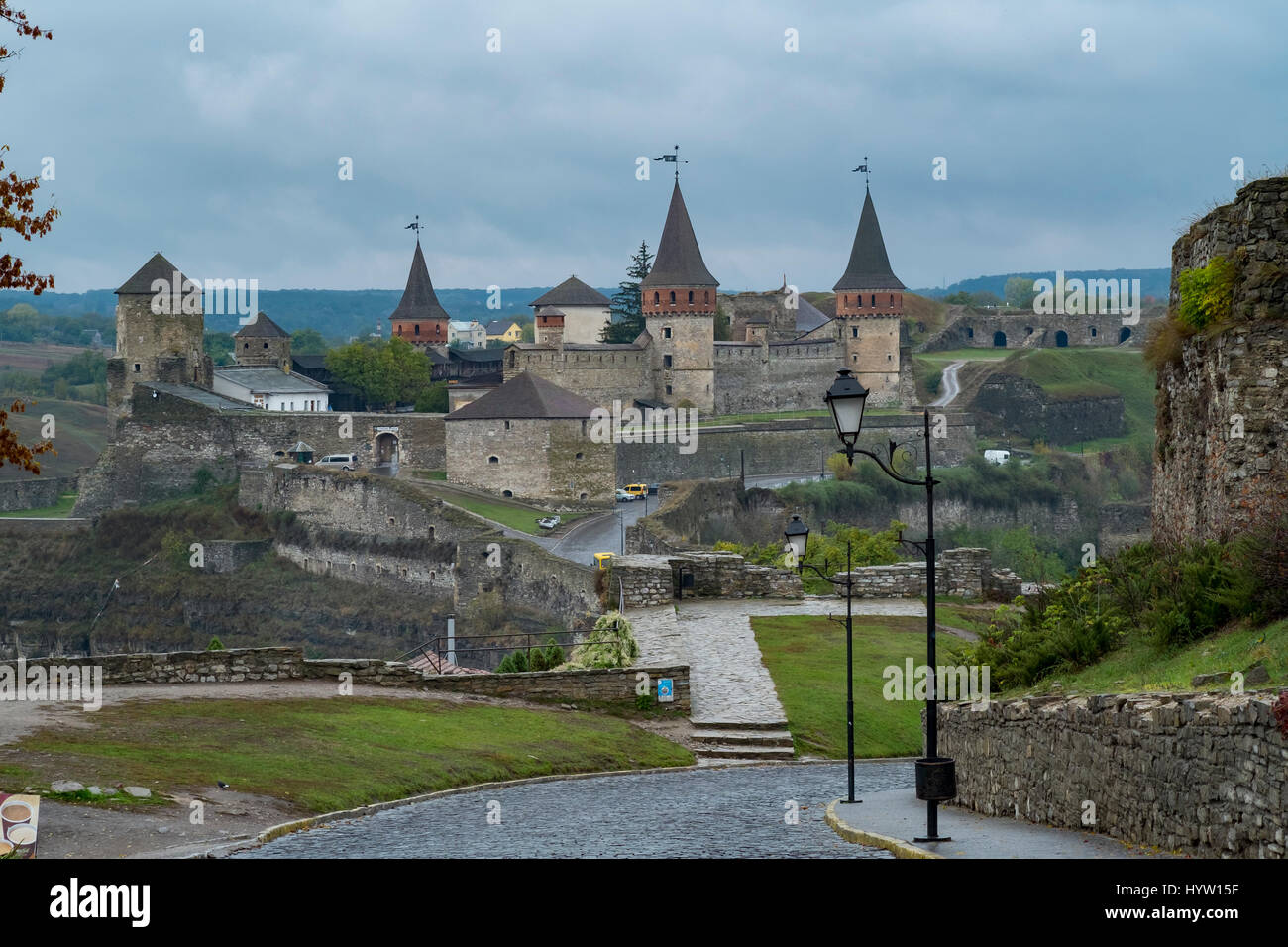 View of the Most Zamkowy and Castle of Kamianets-Podilskyi in Western Ukraine taken on a rainy autumn day. The cobbled street leads the eye across the Stock Photo