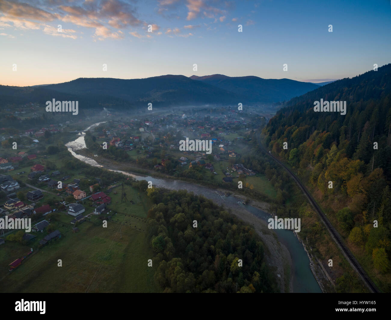 Aerial shot over the village of Mykulychyn in the Carpathian region of Western Ukraine as the sun rises behind distant mountains Stock Photo