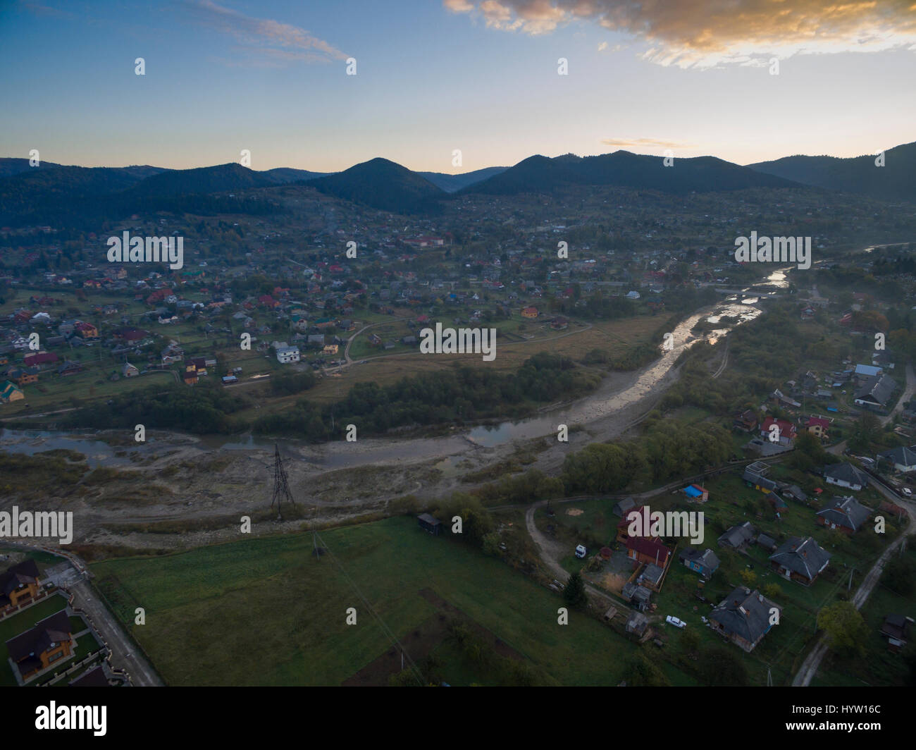 Aerial shot over the village of Mykulychyn in the Carpathian region of Western Ukraine as the sun rises behind distant mountains Stock Photo