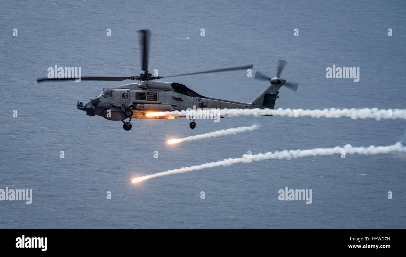 A U.S. Navy MH-60R Sea Hawk helicopter fires chaff flares during a training exercise near the Nimitz-class aircraft carrier USS Carl Vinson as it transits the Philippine Sea April 24, 2017. The ship is heading toward South Korea as tensions continue to rise between the U.S. and North Korea. Stock Photo