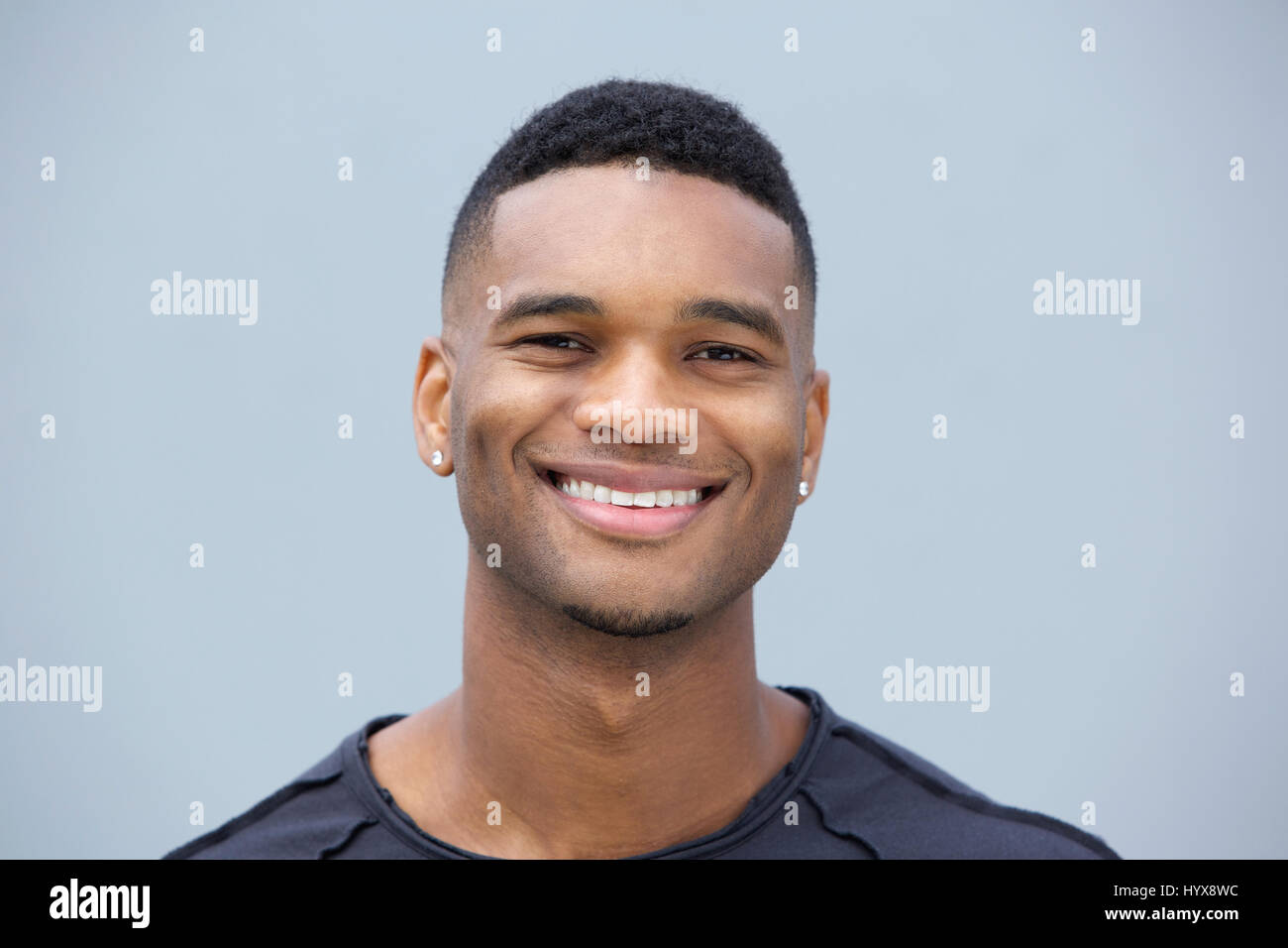 Close up portrait of a young black guy smiling against gray background ...