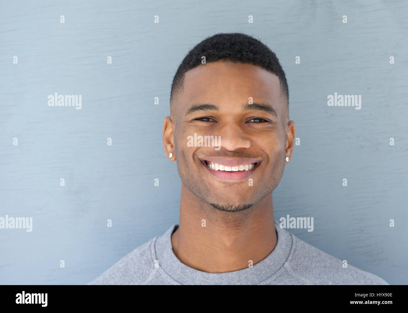 Close up portrait of a handsome young black man smiling on gray ...