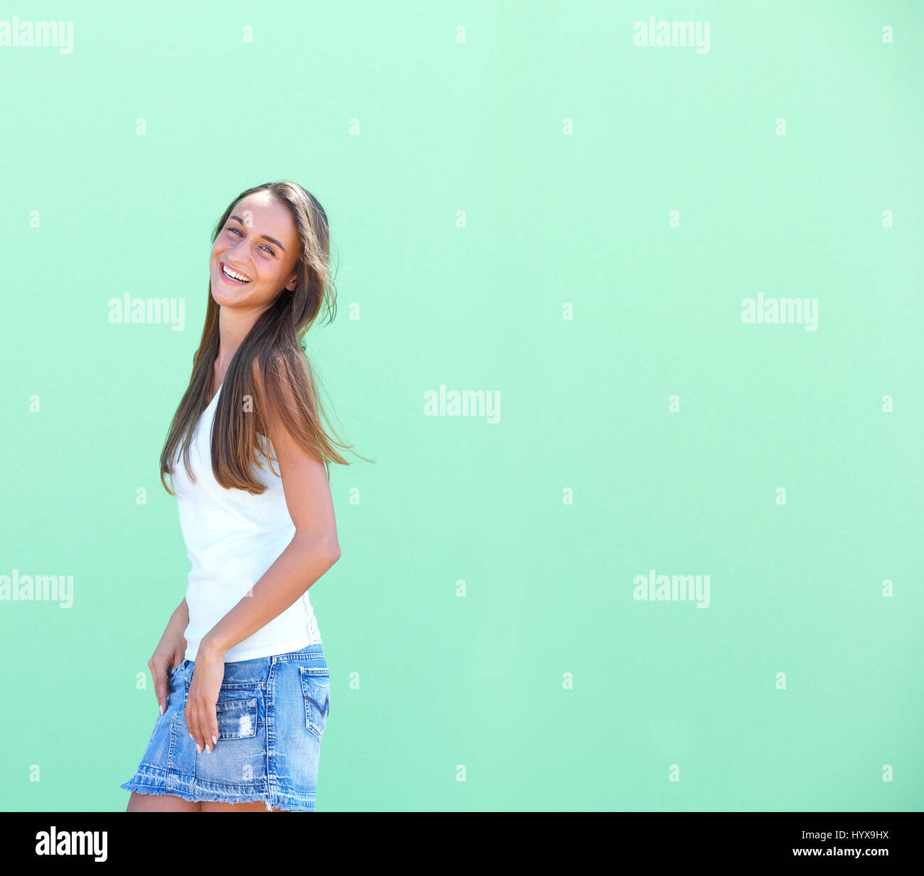 Side view portrait of a cute girl smiling against green background Stock Photo