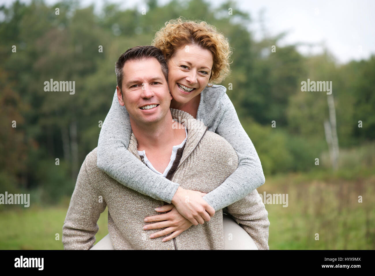 Close up portrait of a smiling couple having fun with piggyback ride ...