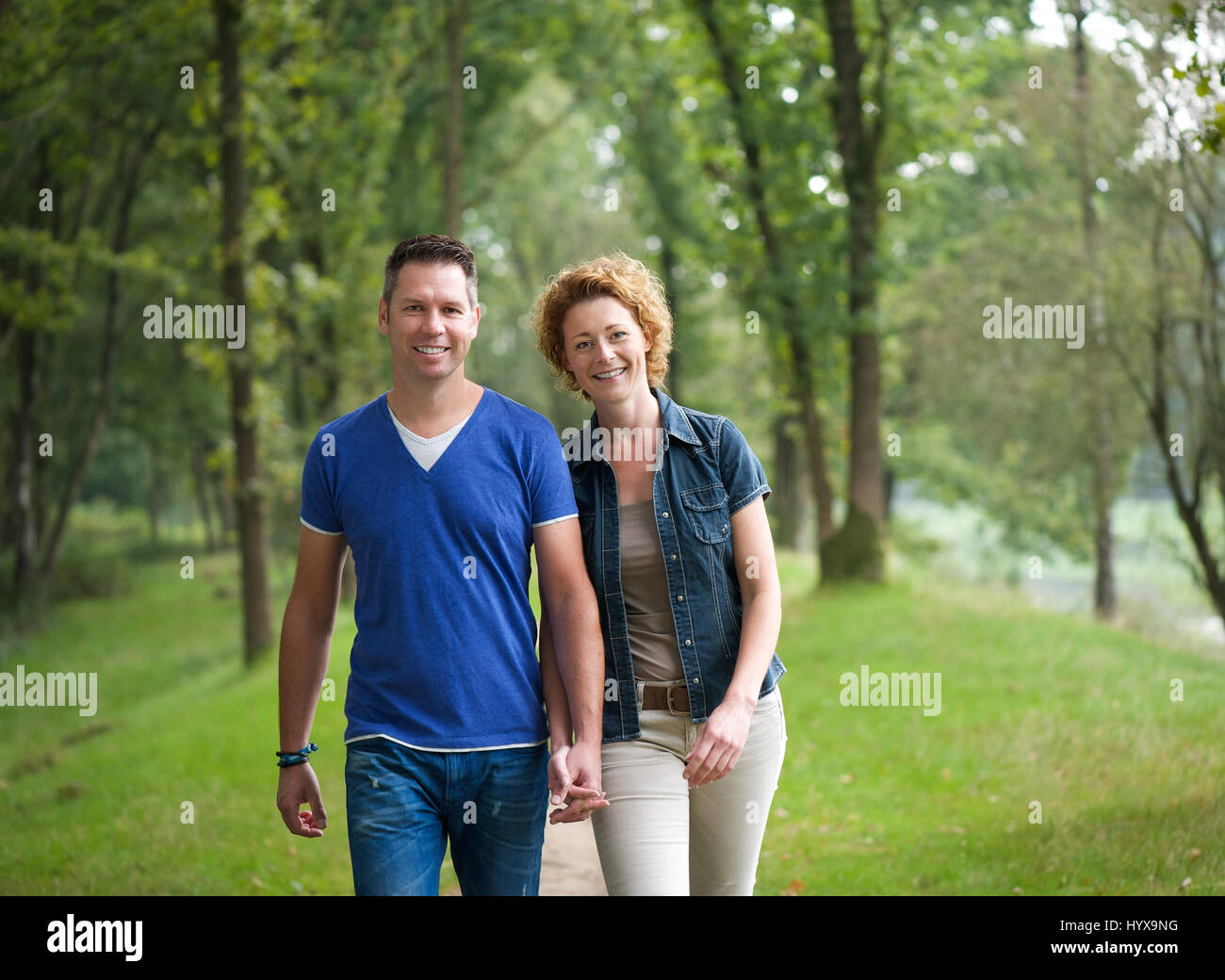 Portrait of a cheerful couple walking together in the woods Stock Photo ...