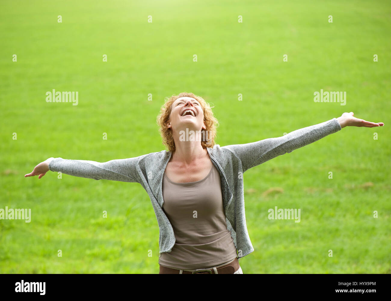Portrait of a carefree older woman smiling with arms open Stock Photo