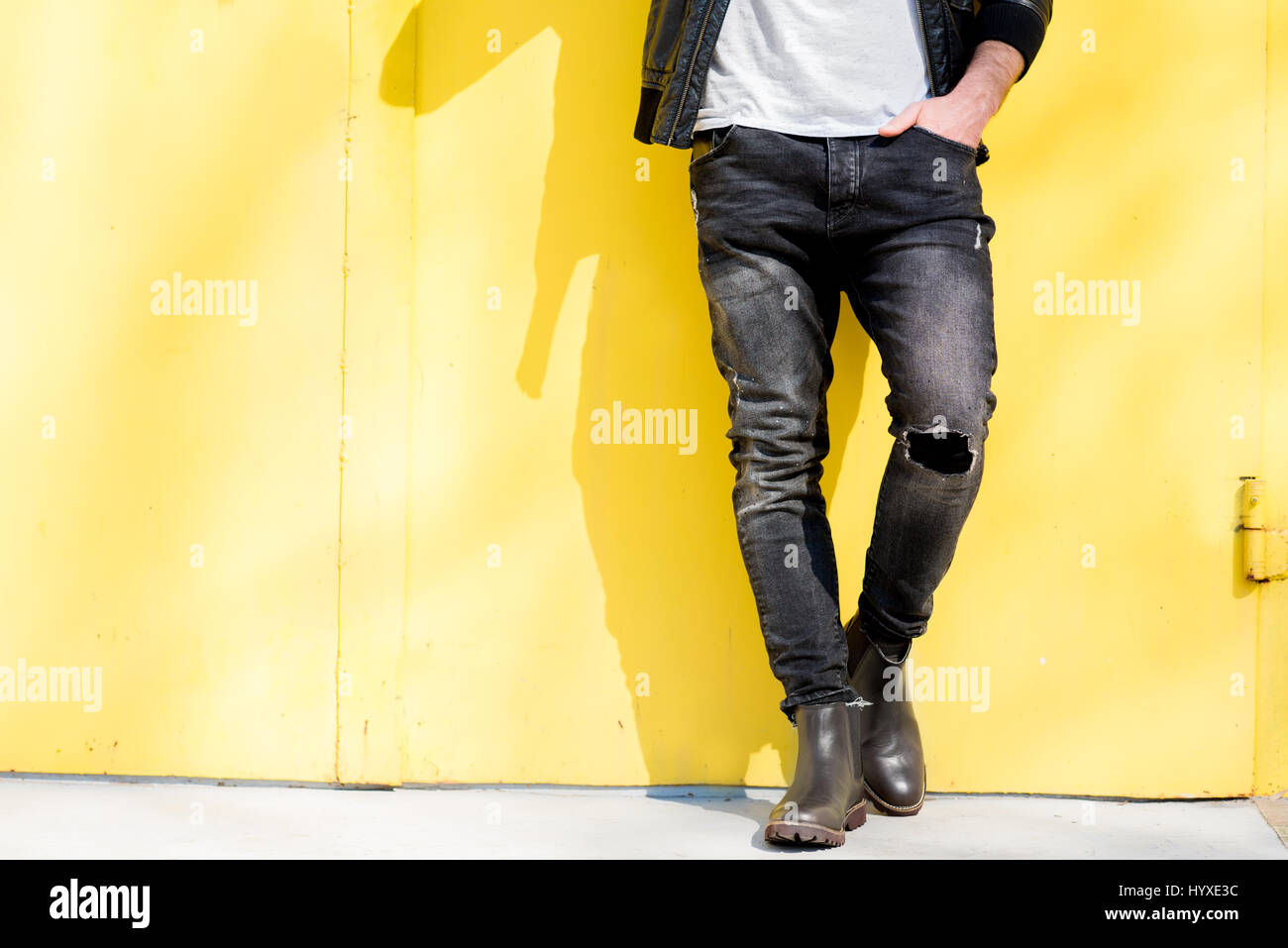 Man dressed in white tshirt, jacket and jeans on the yellow background