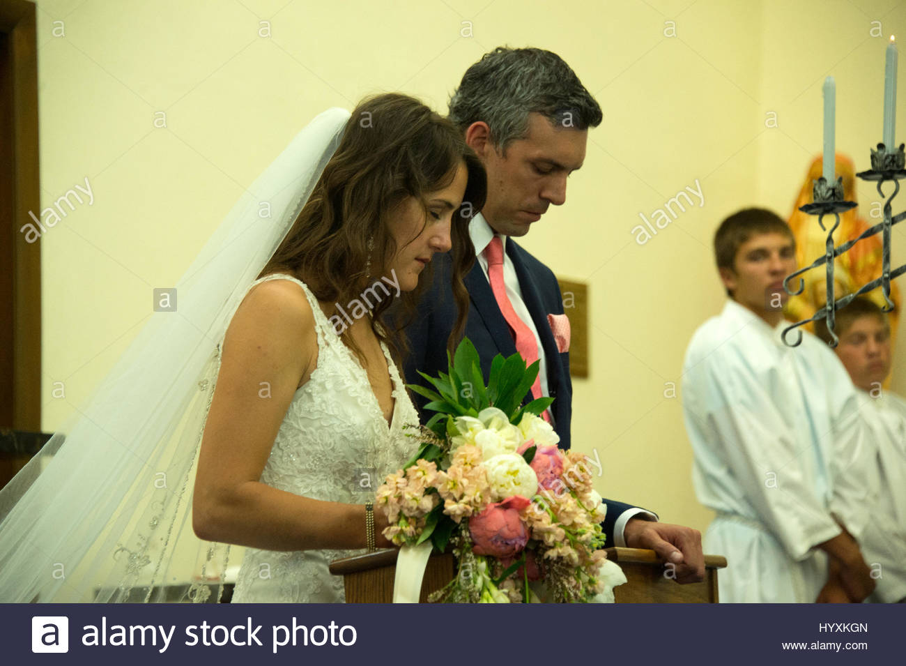 Bride And Groom Kneeling At Altar During Wedding Ceremony Stock