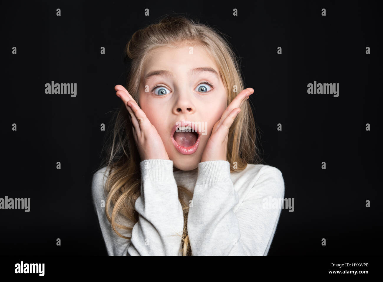 Cute shocked blonde girl looking at camera on black Stock Photo - Alamy