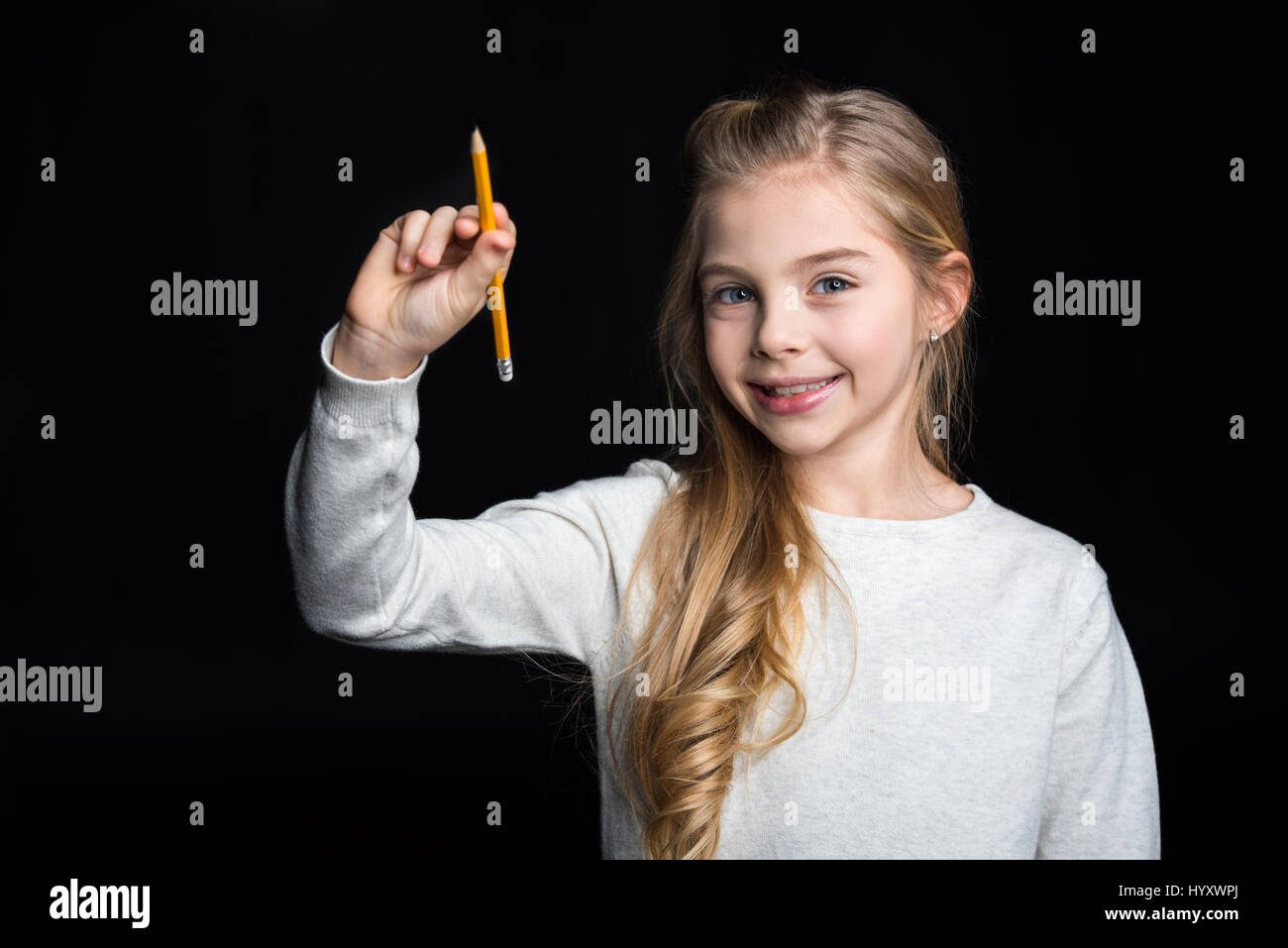 Cute blonde girl holding pencil and smiling at camera Stock Photo - Alamy