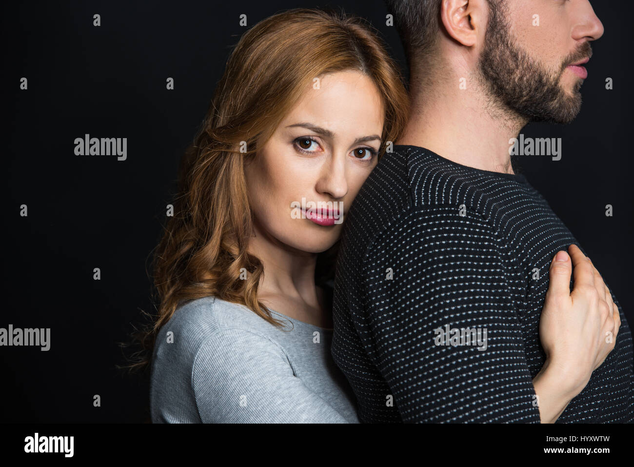 Young beautiful woman hugging her boyfriend from behind and looking at ...