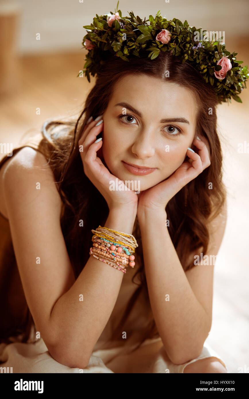 Portrait of smiling young hippie woman in floral wreath looking at camera Stock Photo